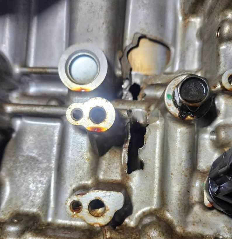 Close-up of an engine block with a hole broken through it