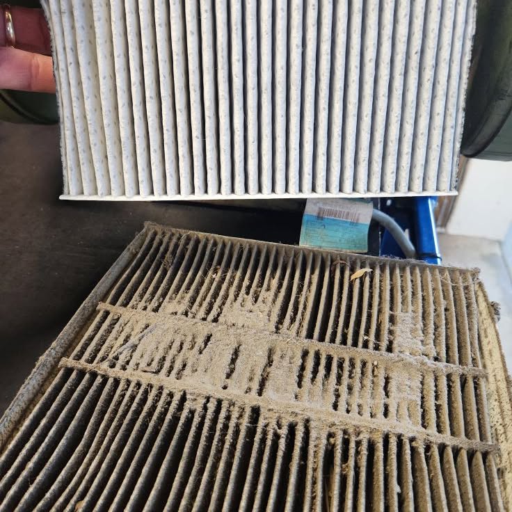 A clean cabin air filter held above a clogged old one